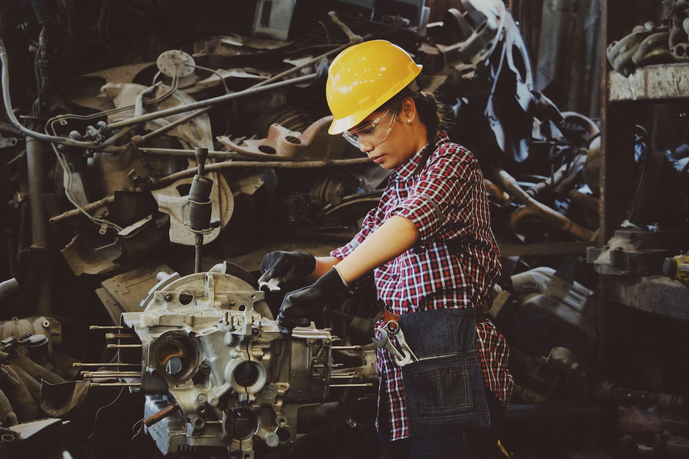 Industrial mechanic in protective gloves and hardhat working on heavy machinery